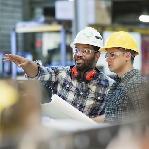 Multi-ethnic workers talking in metal fabrication plant